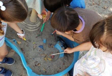 Children playing in a sandbox with toys