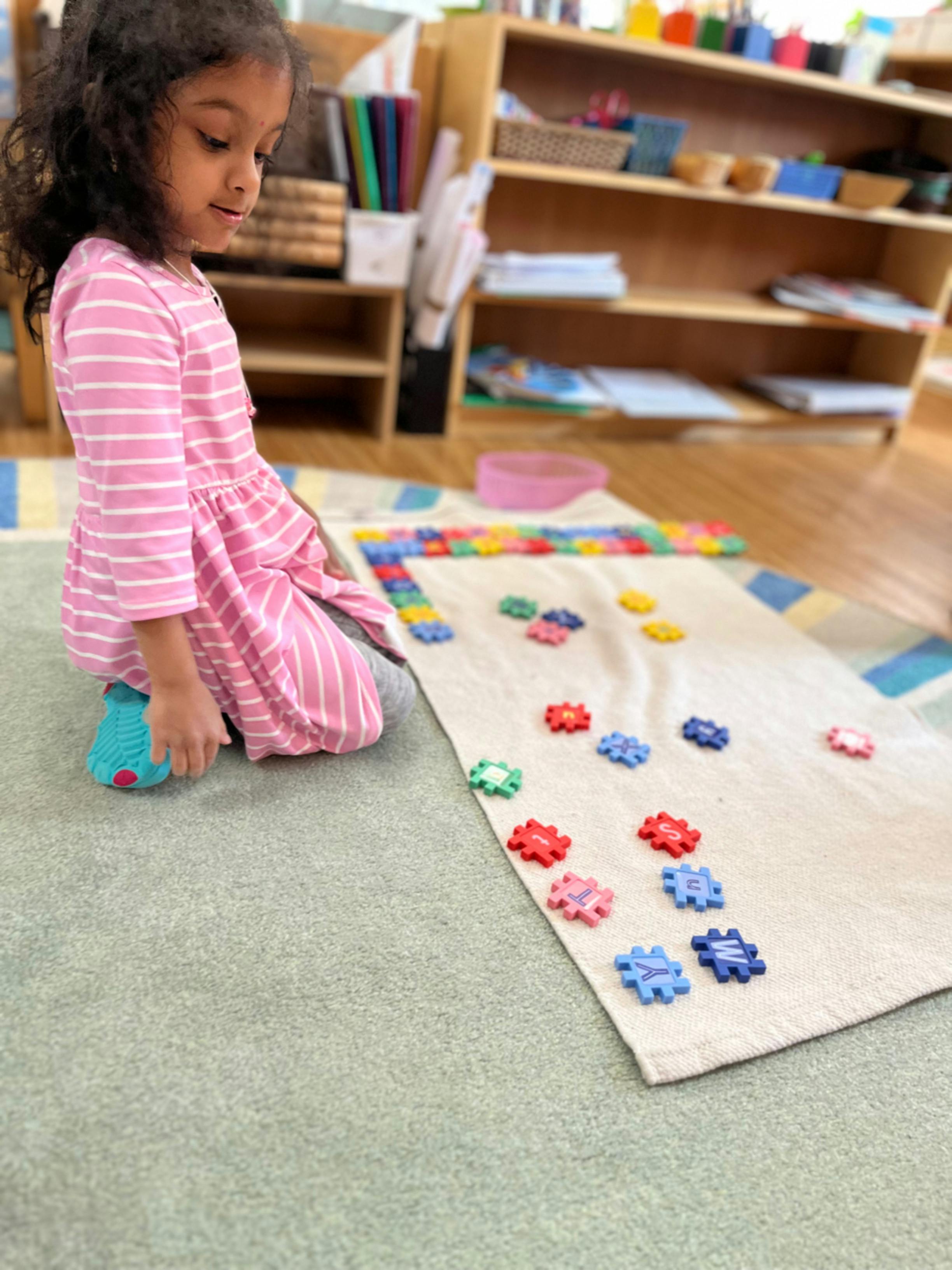 Child kneeling on a rug next to a mat with colorful puzzle pieces