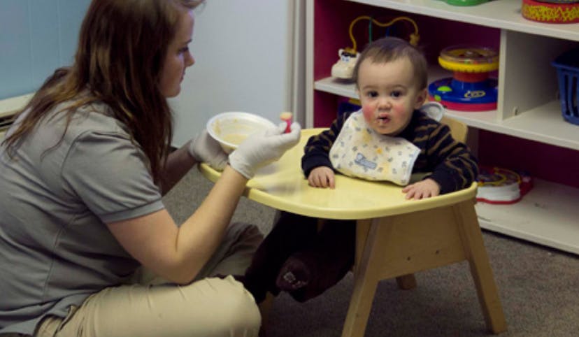 Person feeding a child in a high chair
