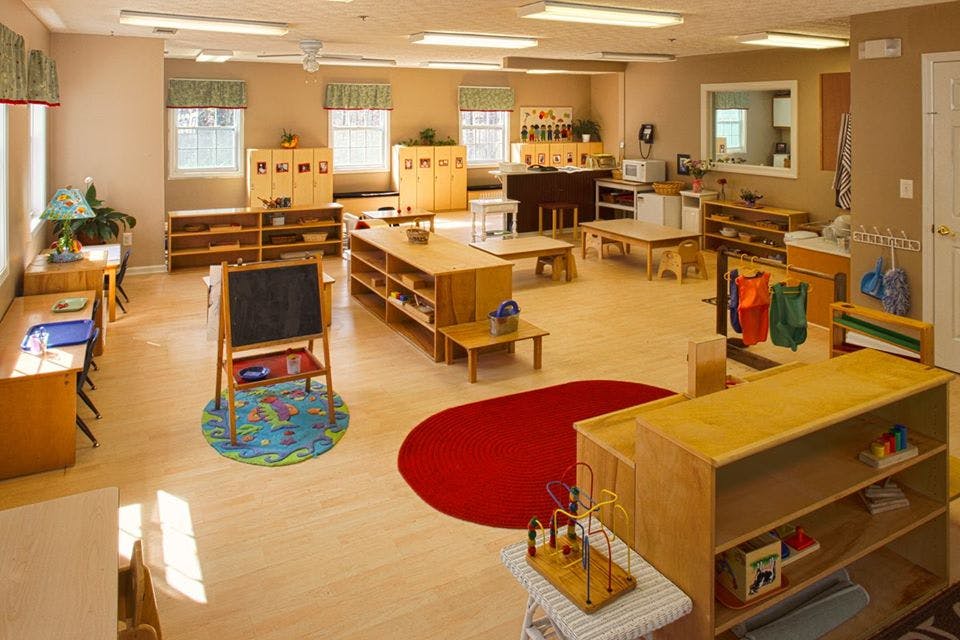 Empty classroom with wooden furniture and red and blue rugs