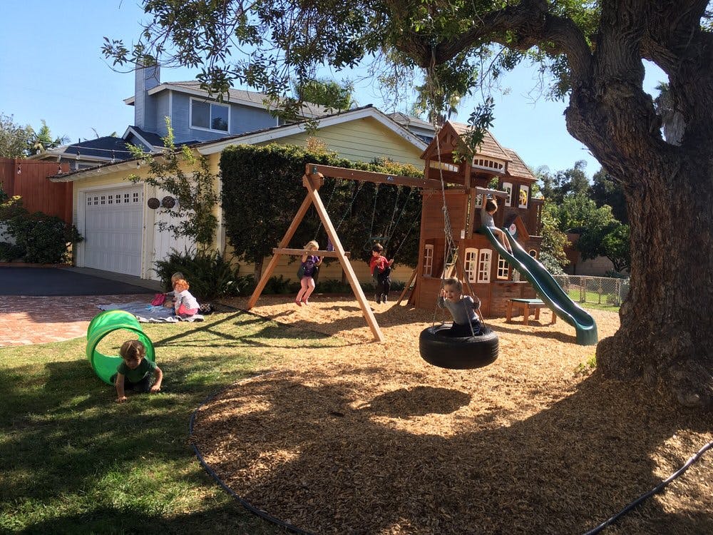 Children playing on a swing set and slide in a backyard