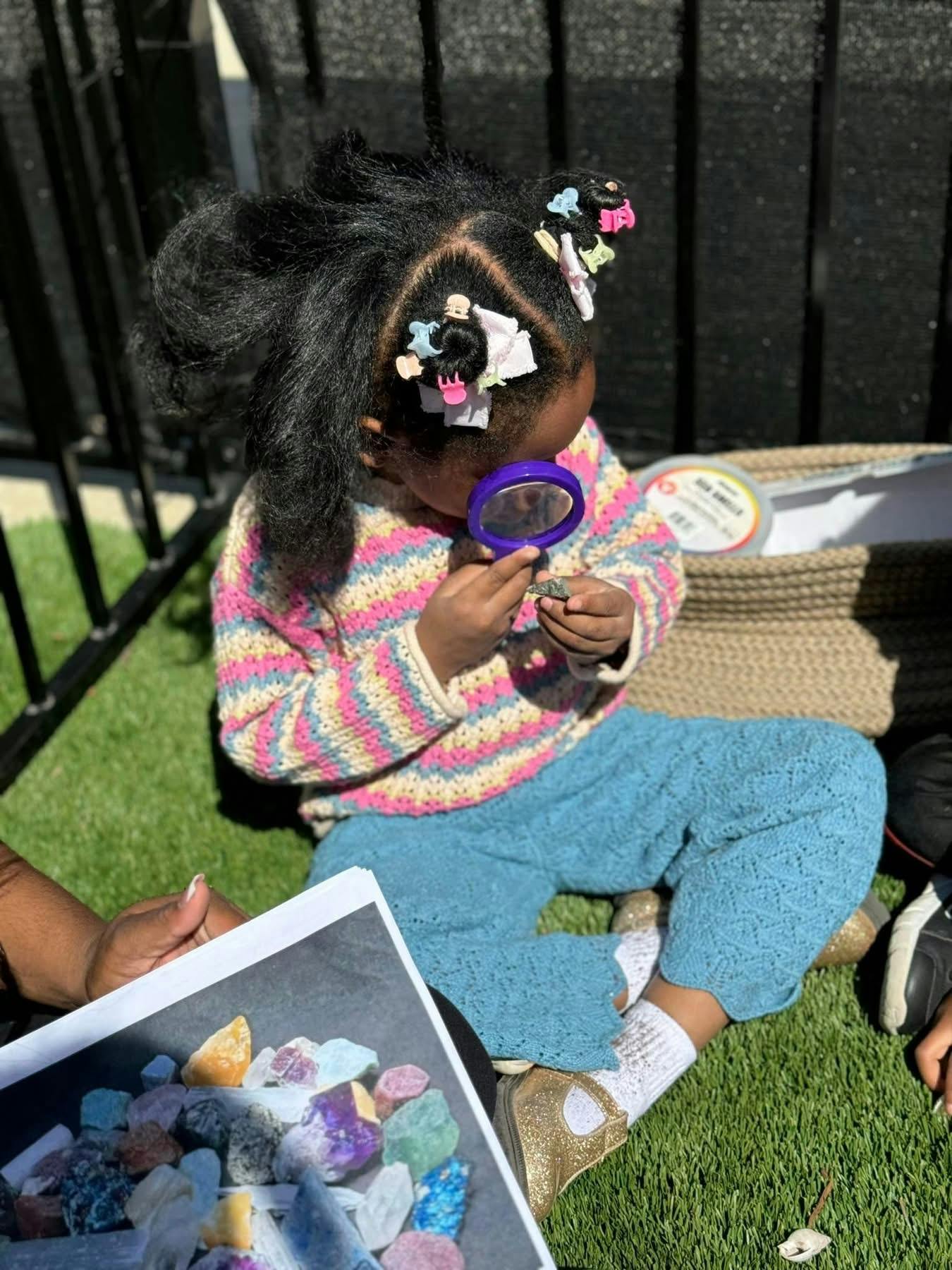 Child sitting on grass looking through a magnifying glass