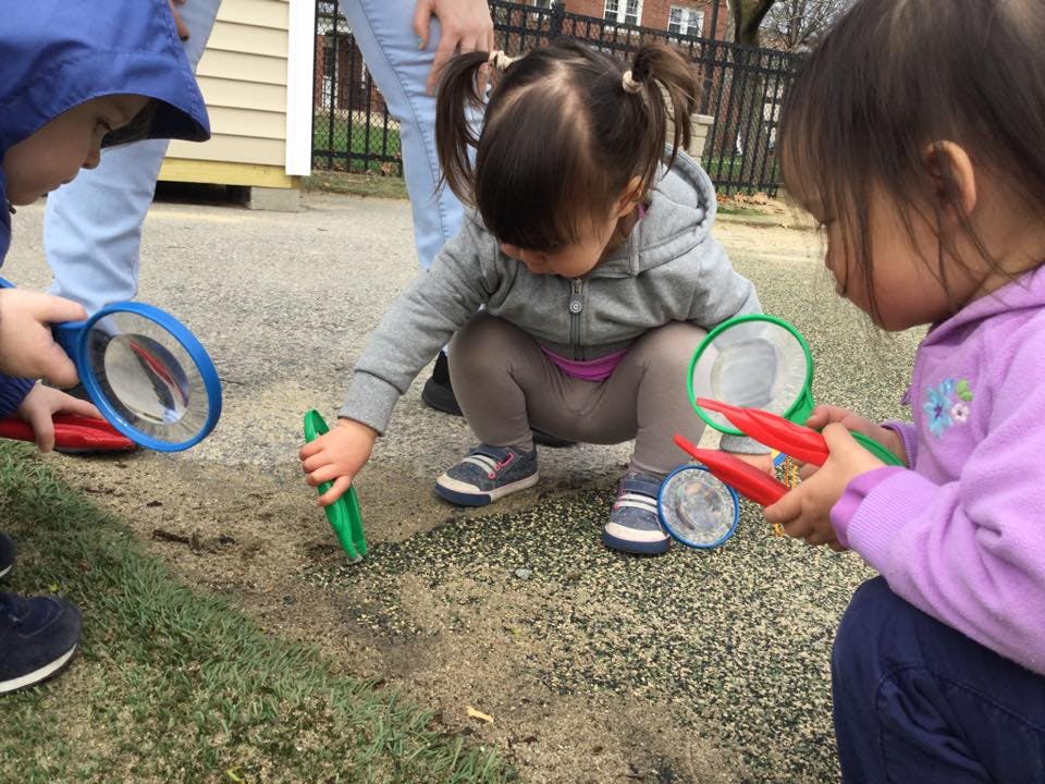 Children playing outdoors with magnifying glass and bug catchers