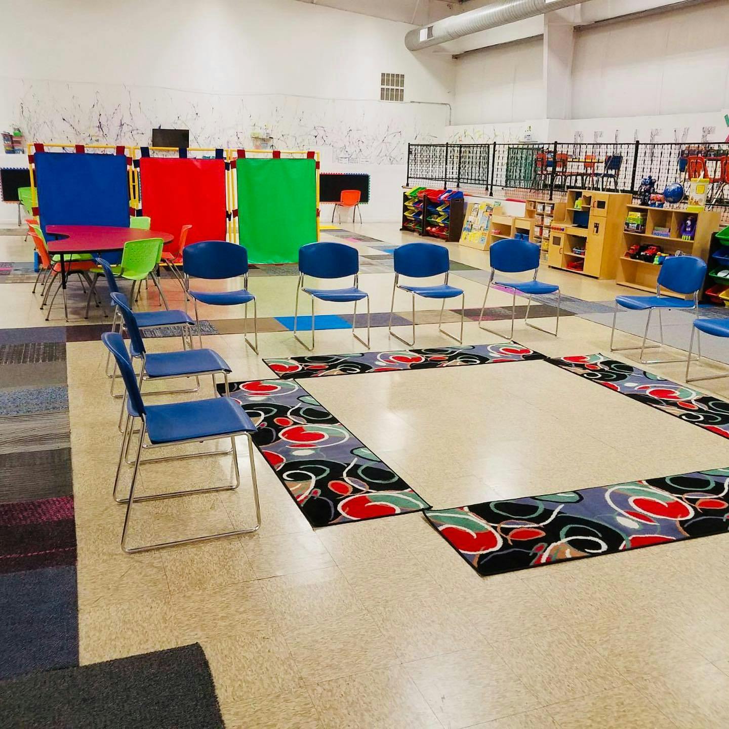 Chairs arranged in a circle around a rug in a classroom