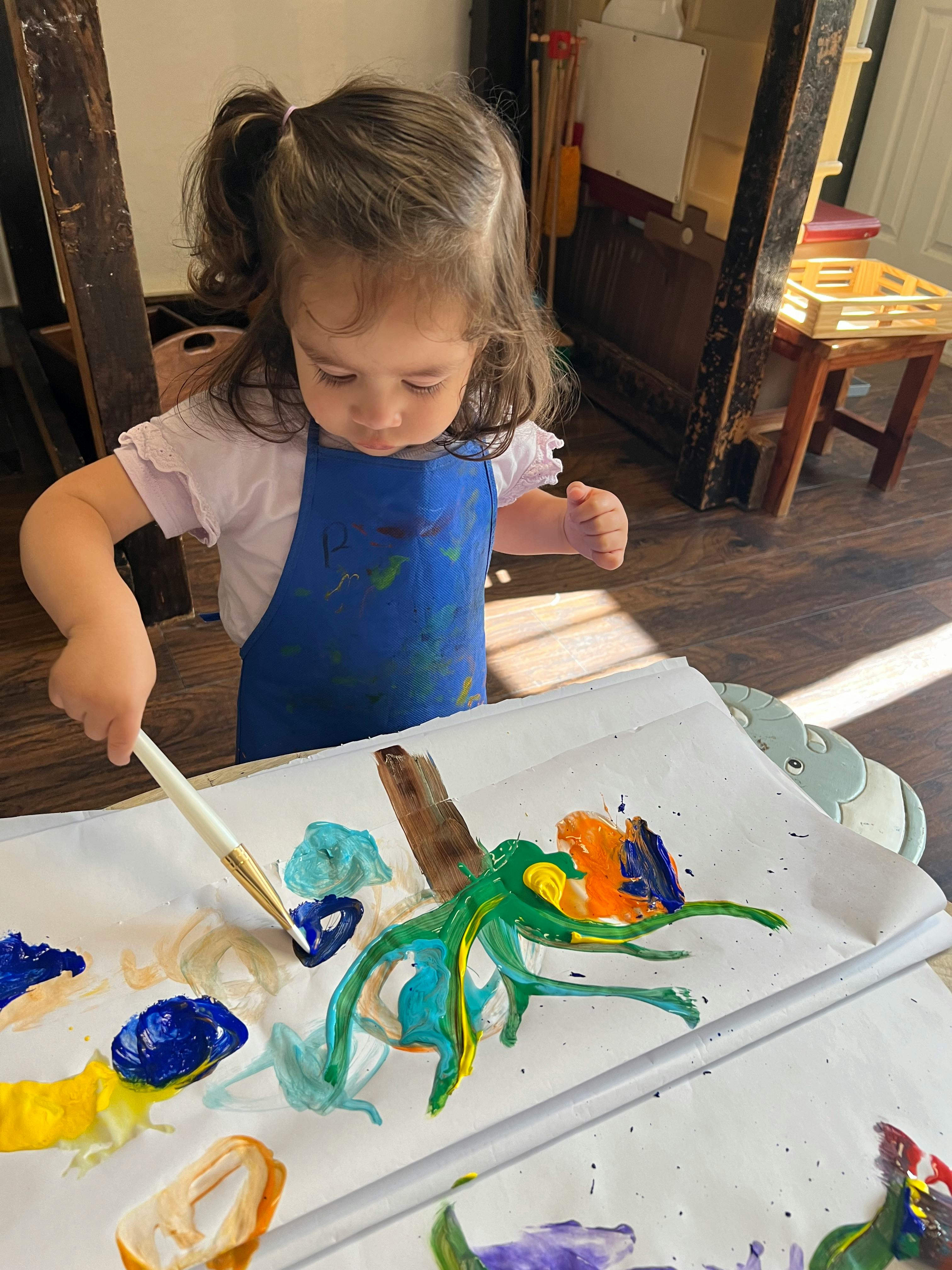 Child in an apron painting on paper with a brush