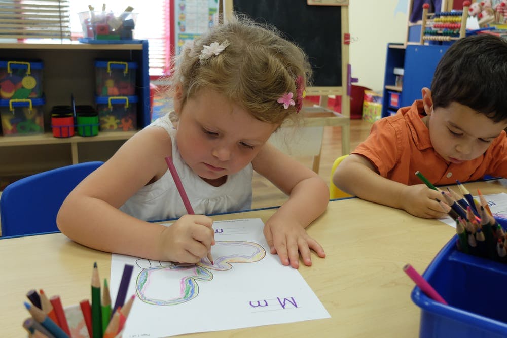 Child coloring a picture at a table in a classroom