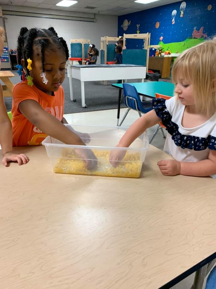 Two children playing with a sensory bin in a classroom