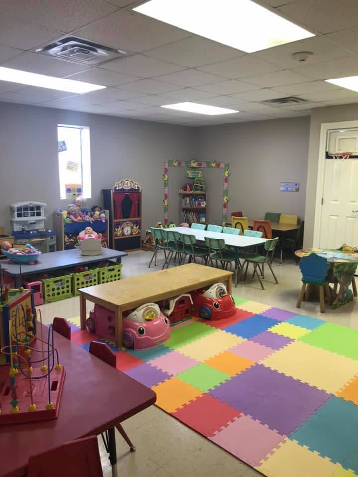 Playroom with colorful floor mats, small tables, and toys