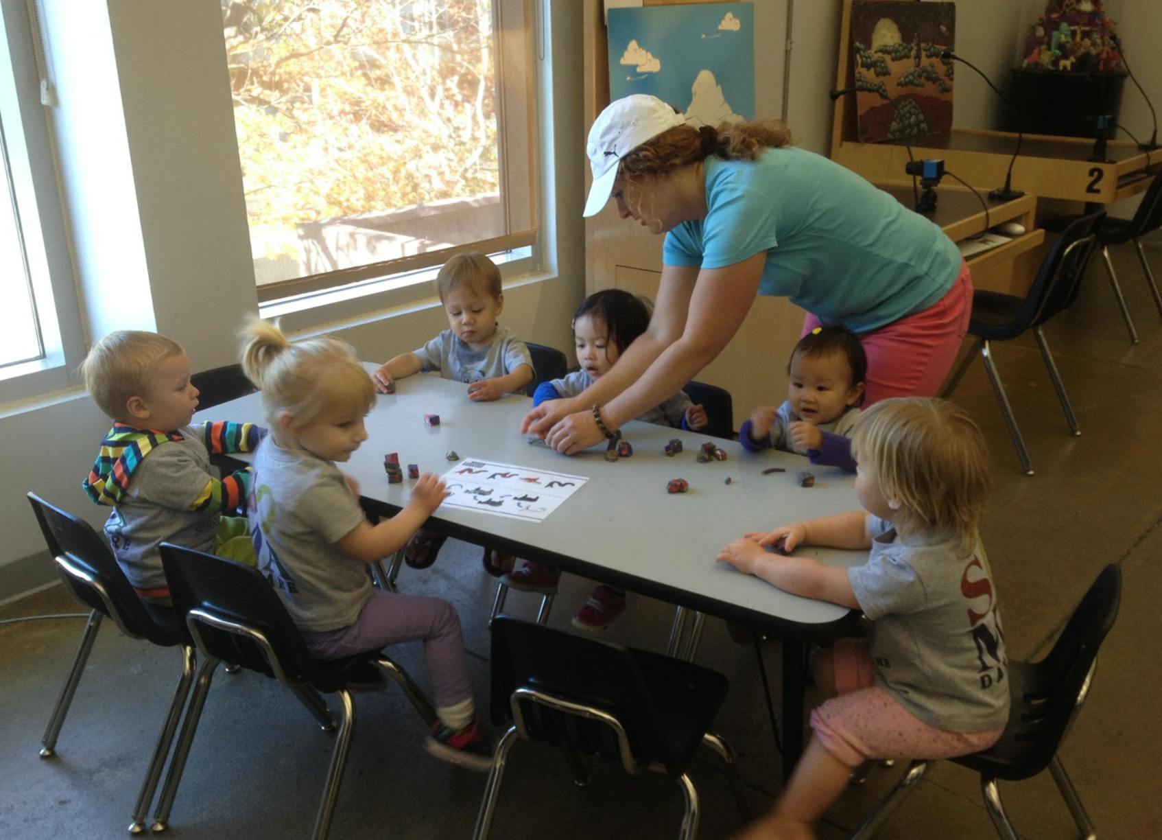 Adult and multiple children at a table with small objects