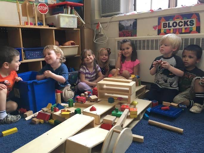 Children playing with wooden blocks in a classroom