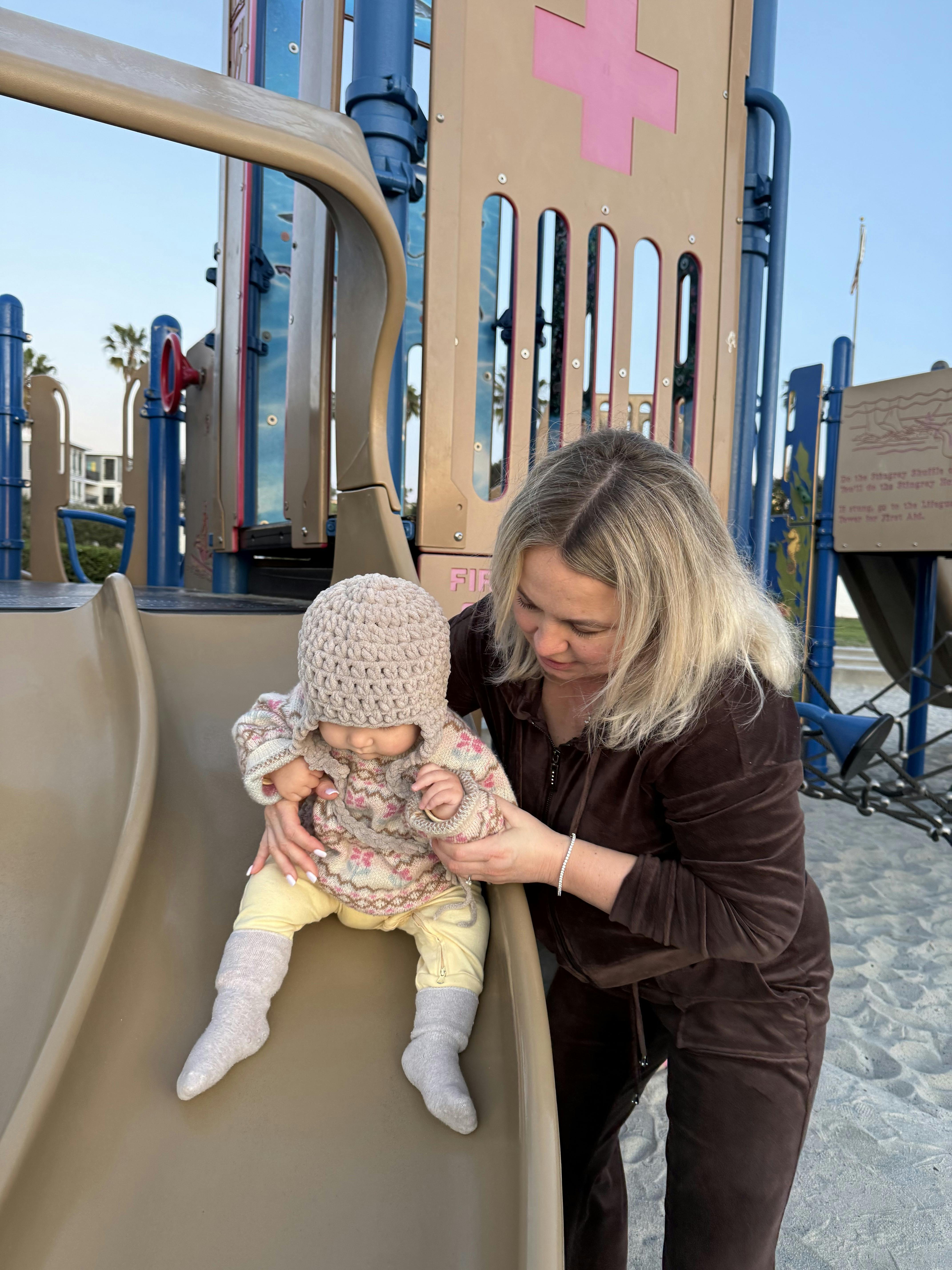 person helping a child down a playground slide