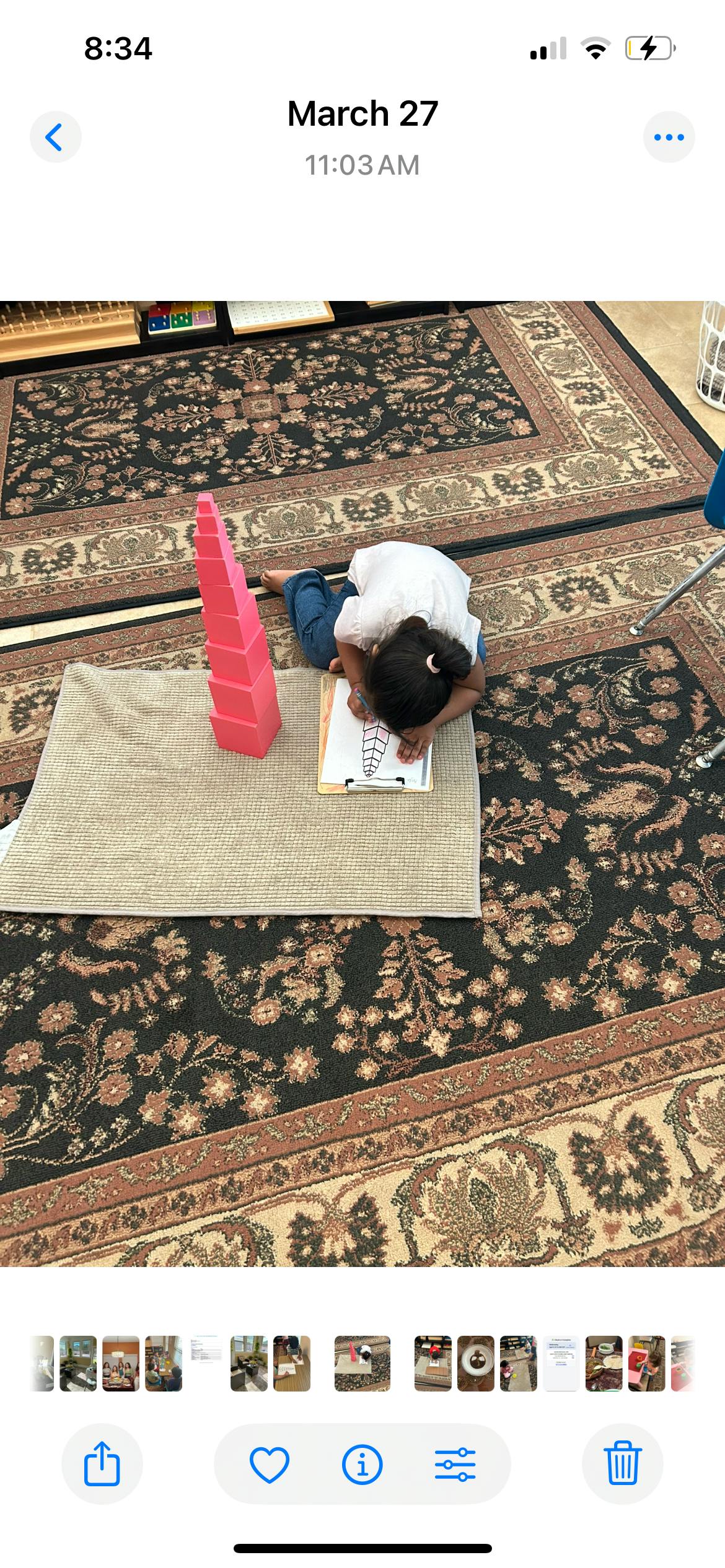 Child drawing on a clipboard next to a pink tower