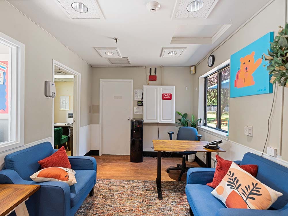 Waiting room with two blue couches, a desk, and a window overlooking greenery