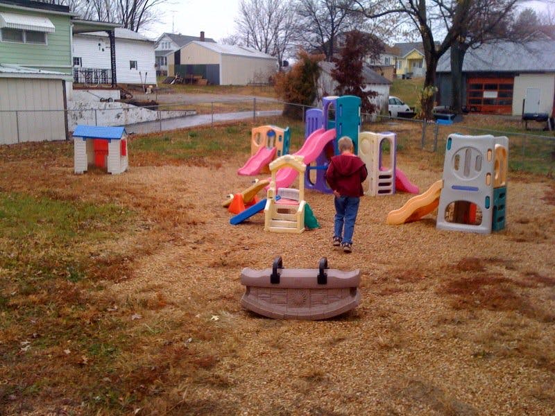 Child standing on a playground with multiple slides and play structures