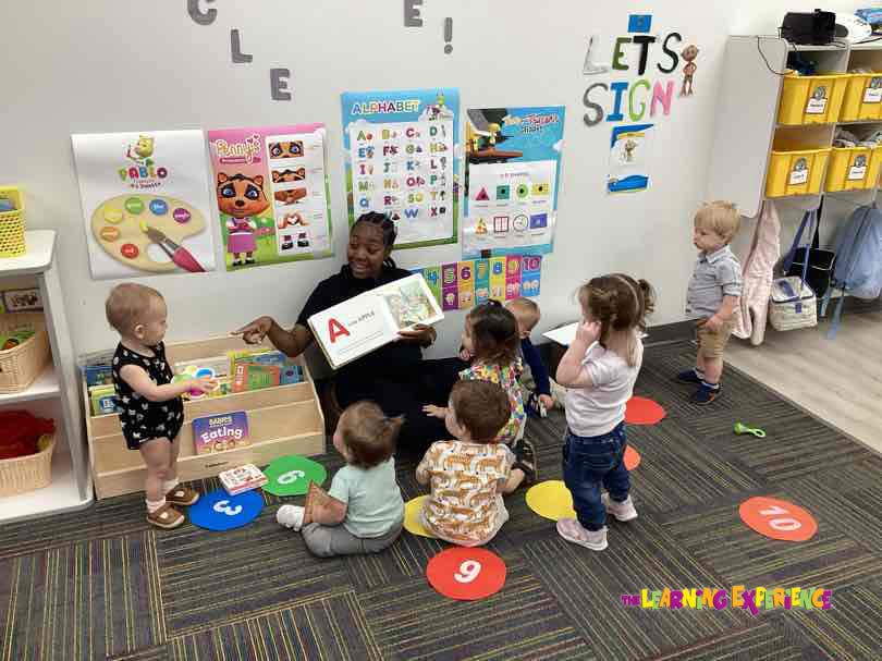 Adult reading a book to a group of children in a classroom