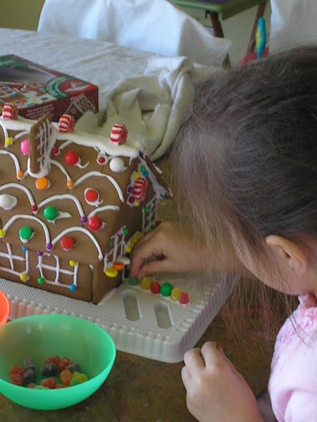 Child decorating a gingerbread house with candies