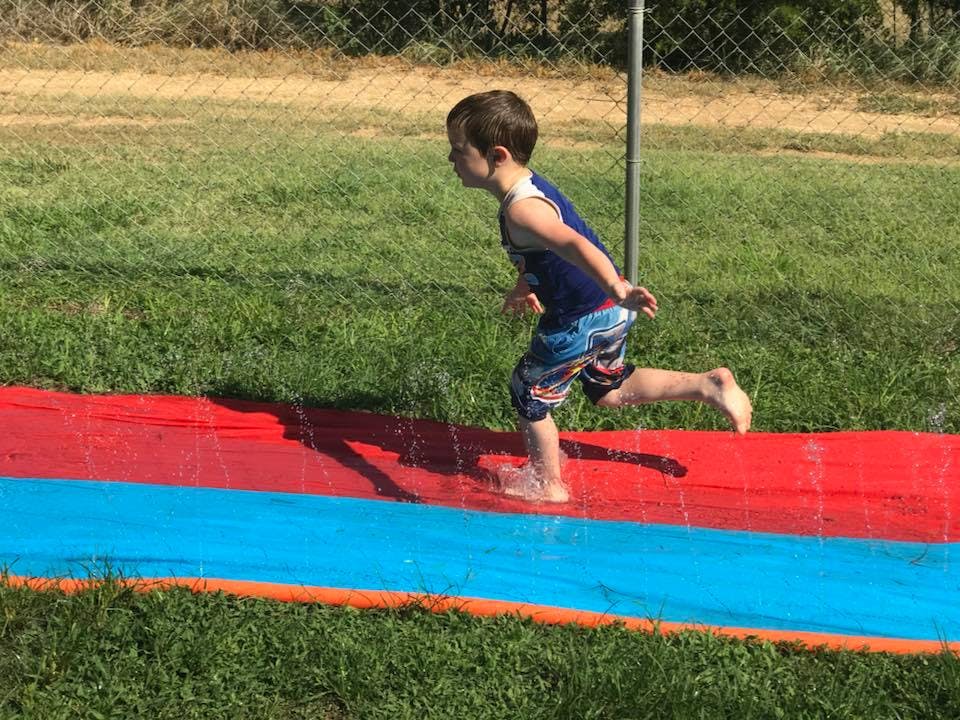 Child running on a red and blue slip and slide