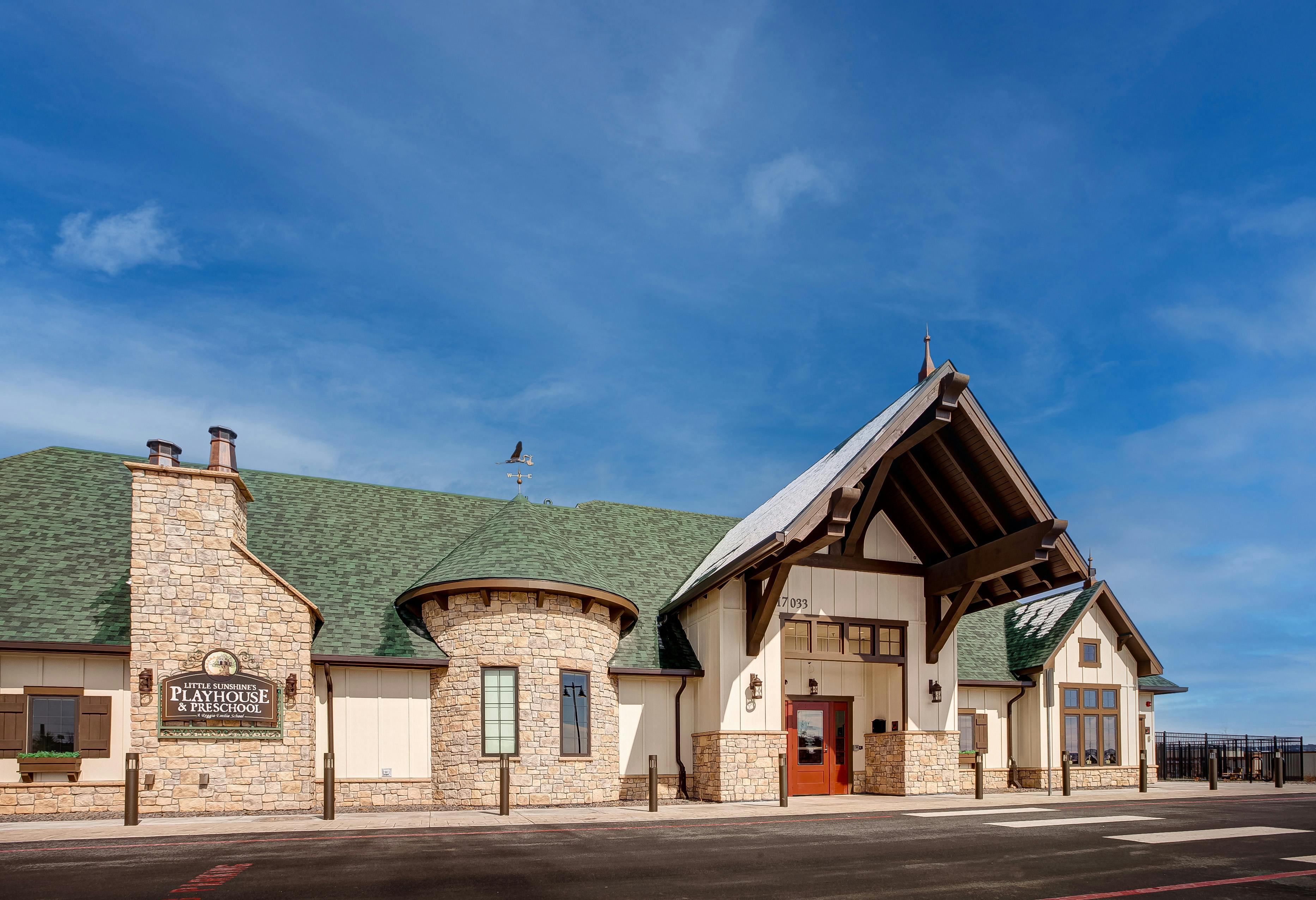 Building with stone and stucco exterior, green roof, and prominent entrance