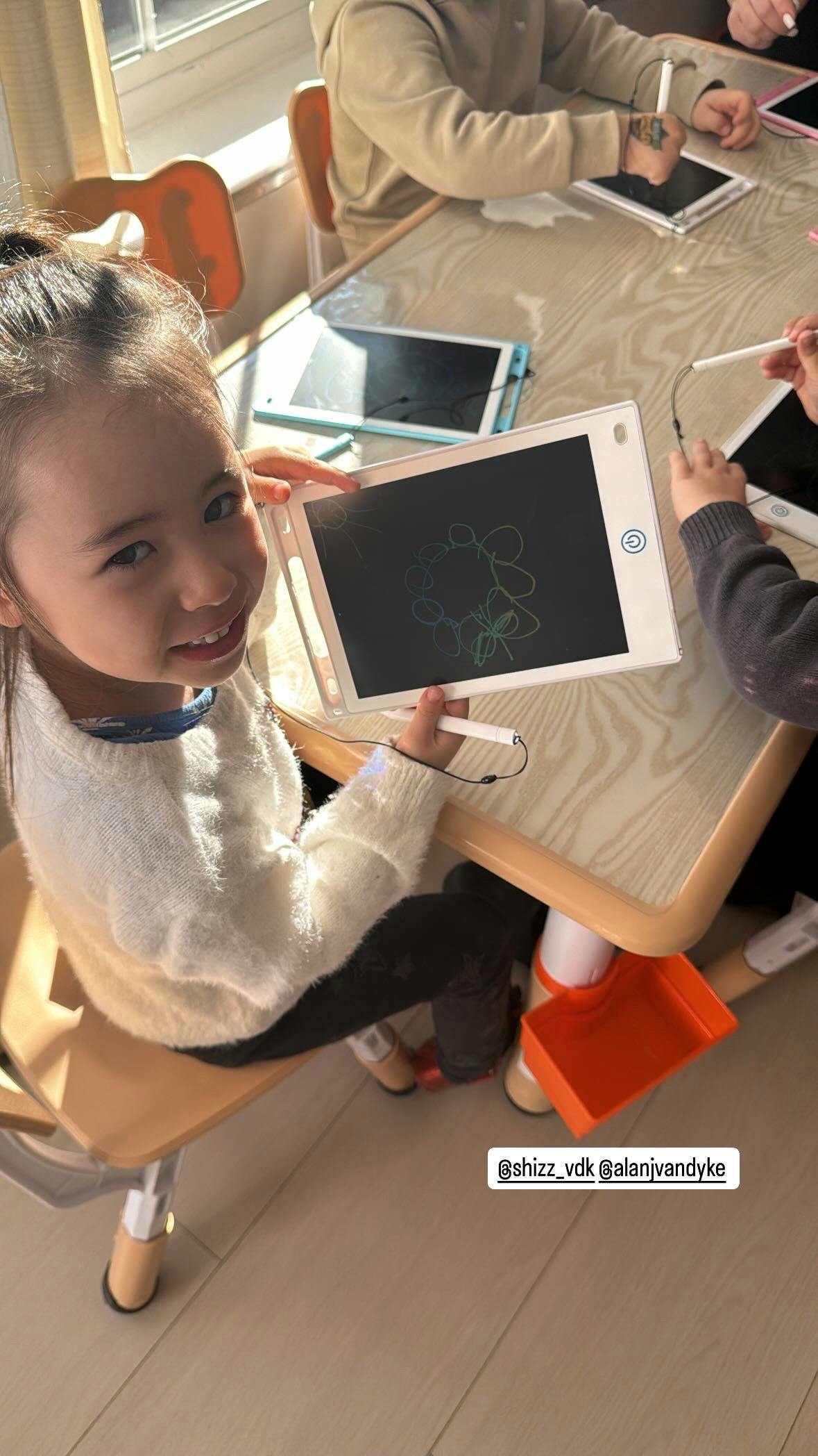 Child holding a drawing tablet with a drawing on the screen