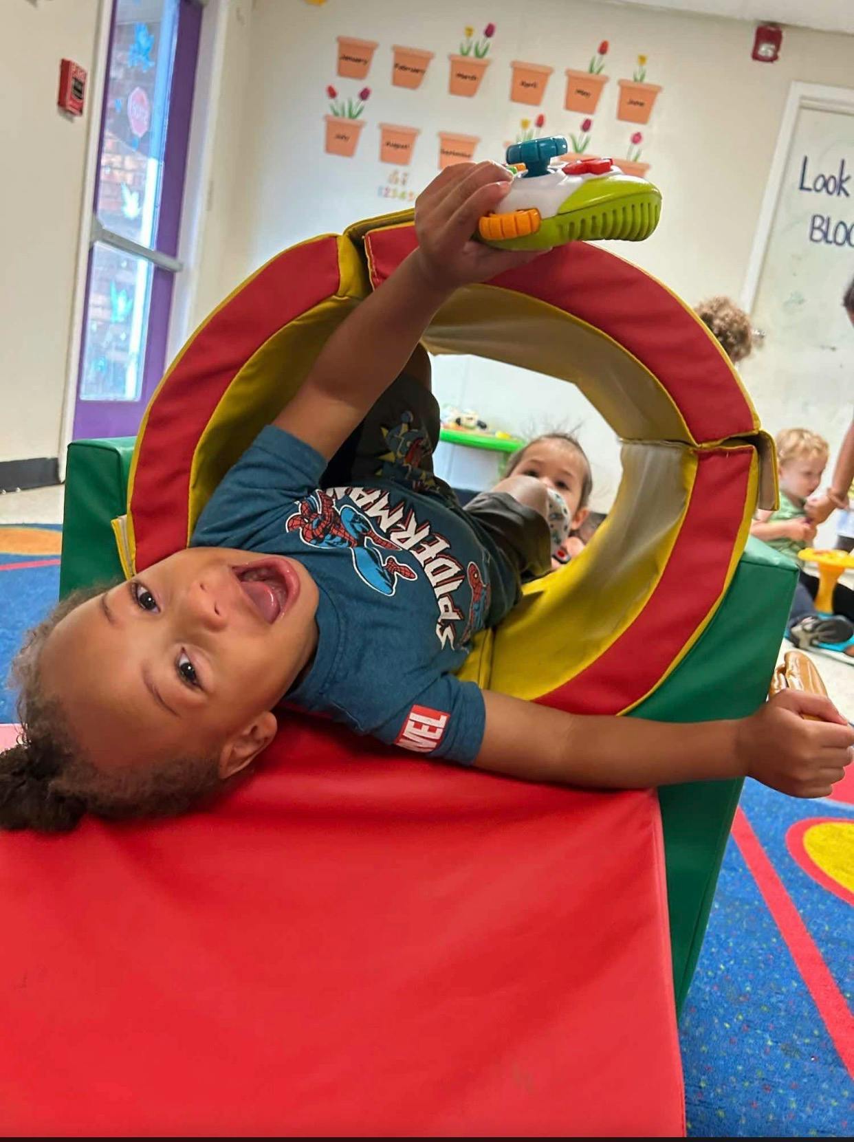 Child playing in a colorful soft tunnel in a classroom