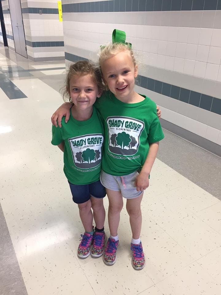Two children in green shirts with "Shady Grove" text, standing with arms around each other