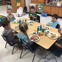 Children sitting at a table with plates of food