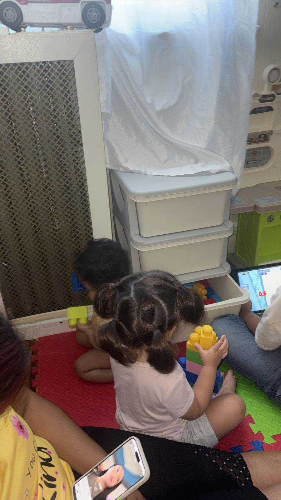 Children sitting on a play mat stacking colorful plastic building blocks