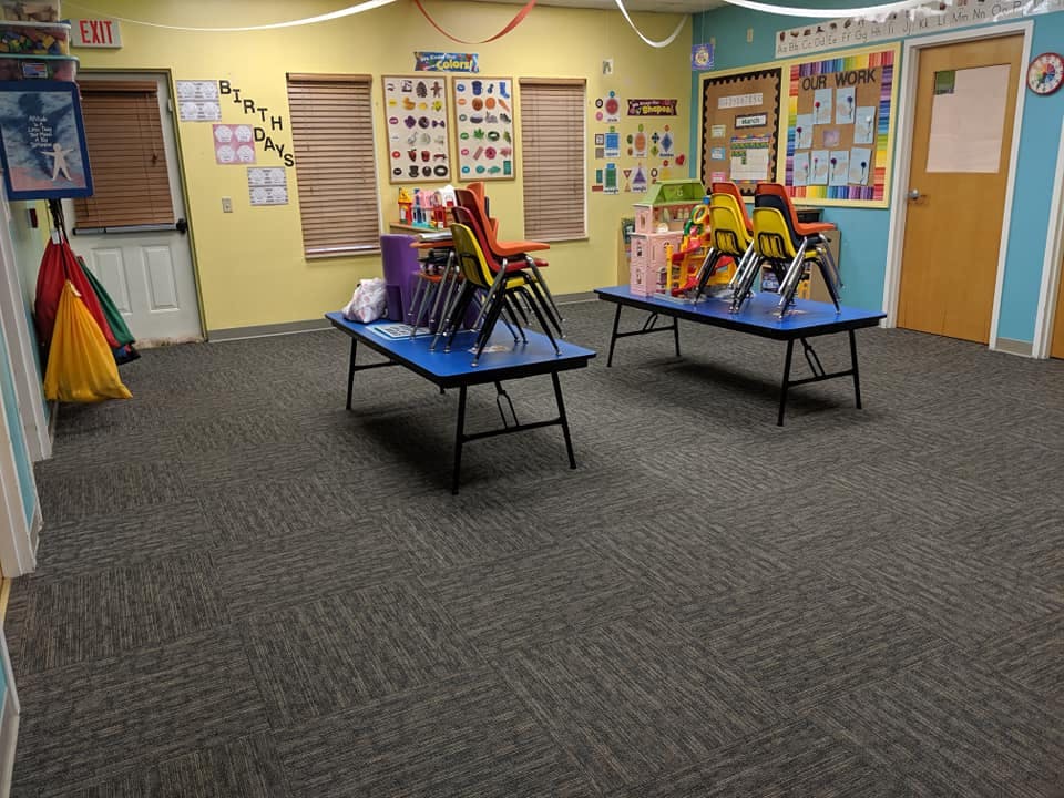 Classroom with two blue tables and stacked chairs