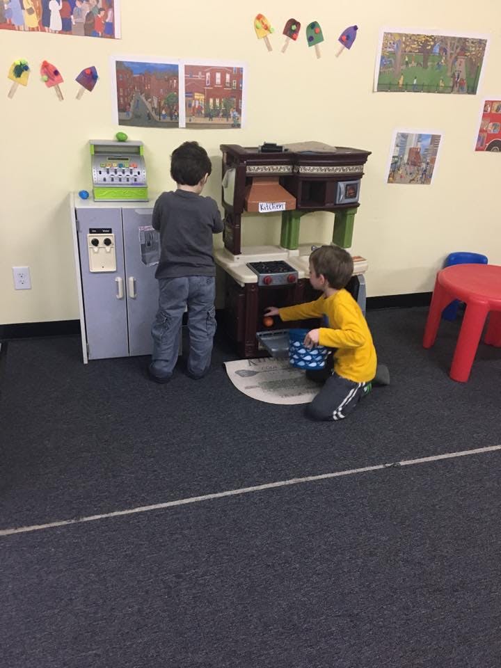 Two children playing with toy kitchen and cash register