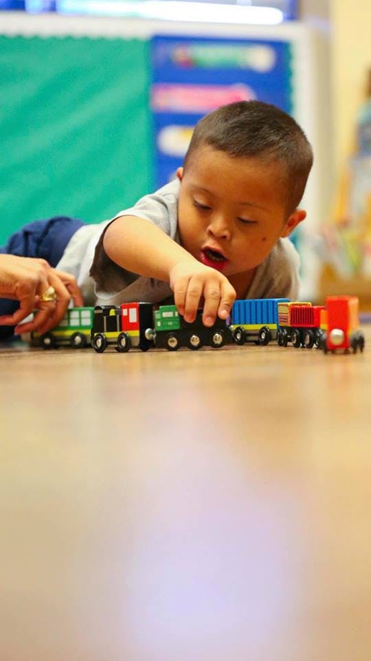 Child playing with a toy train on the floor