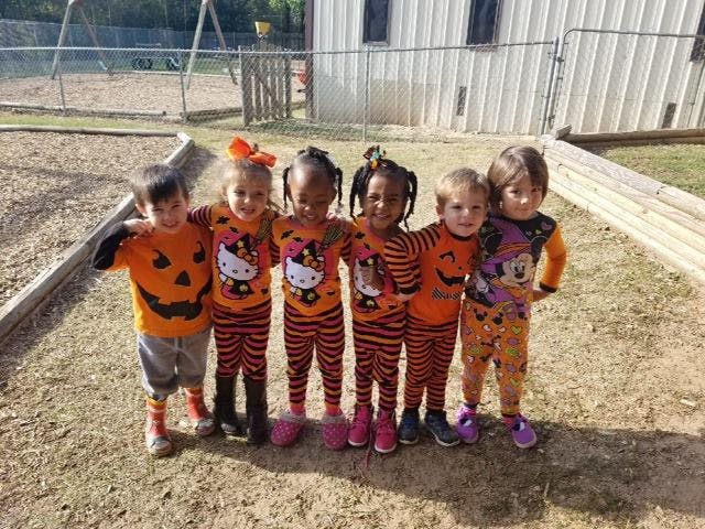 Six children in Halloween costumes standing together outdoors