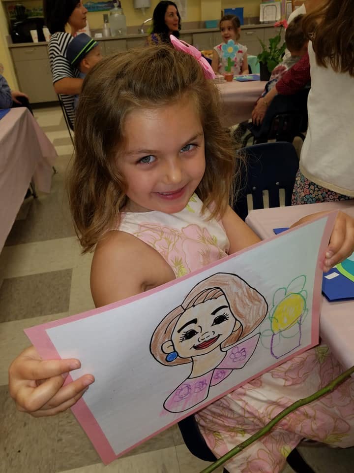 Child holding up a drawing of a person