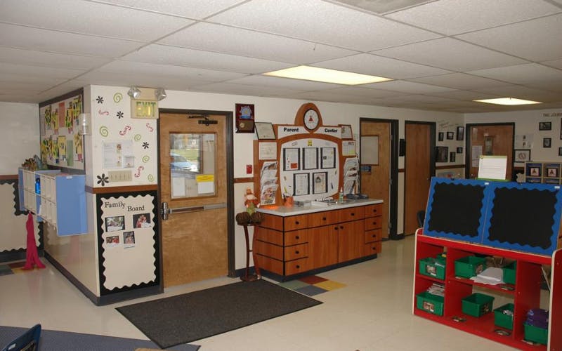 An empty childcare or classroom entrance area with cubbies, bulletin boards, and doors