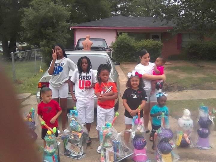 Group of people and children standing outdoors with gift baskets