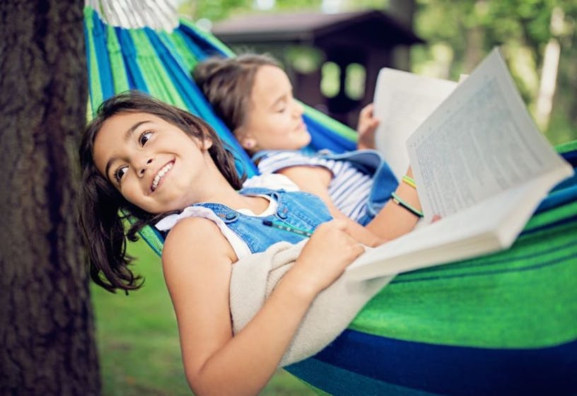 Two children reading in a hammock