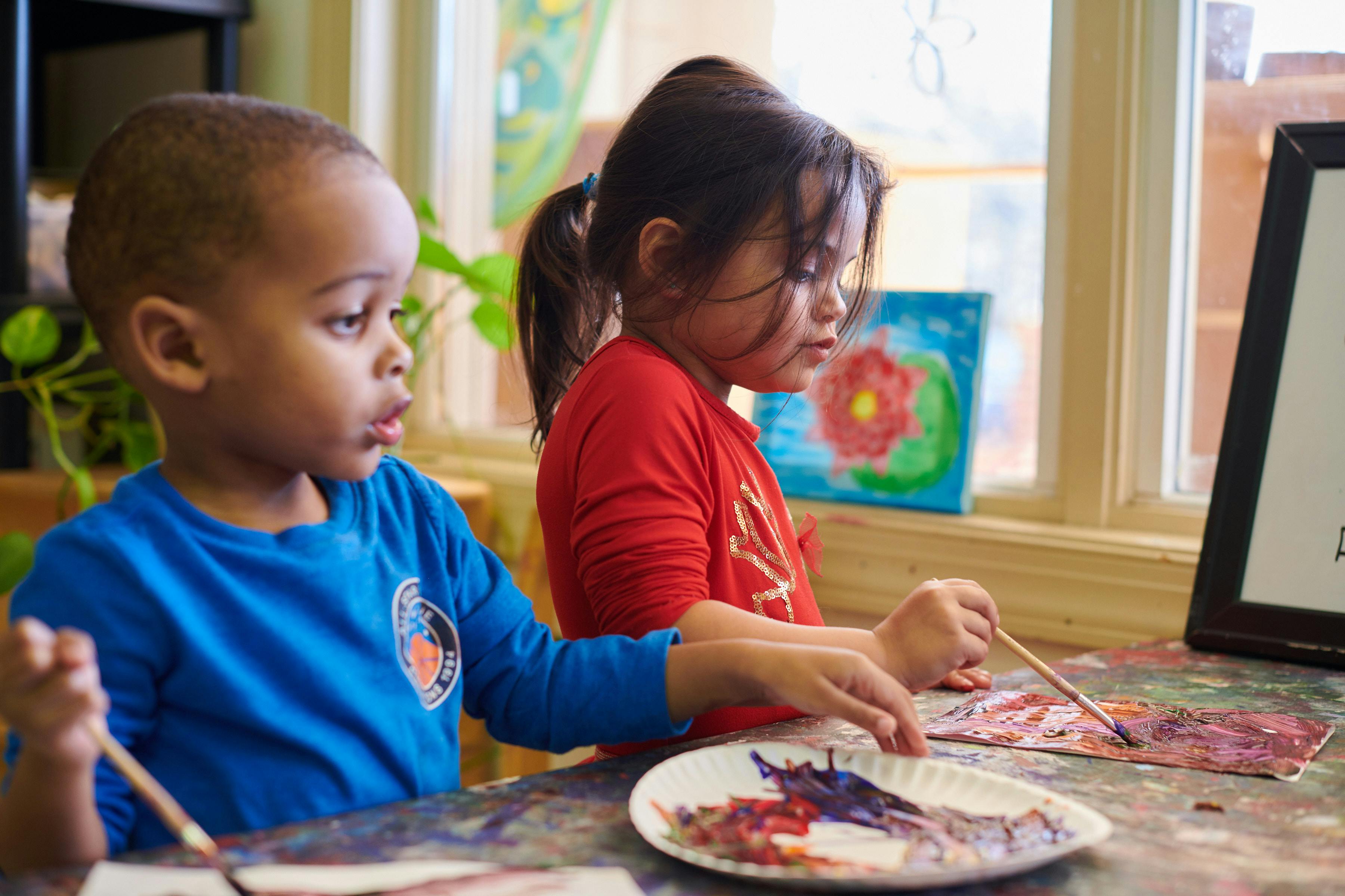 Two children painting at a table