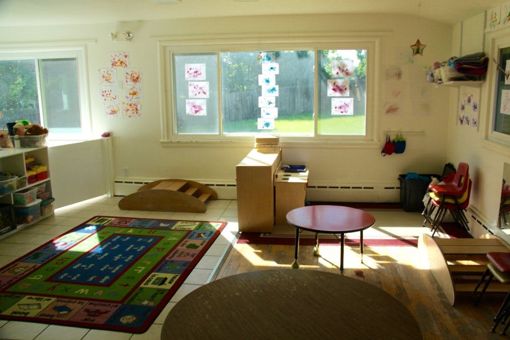 Classroom with colorful rug, small tables, and windows