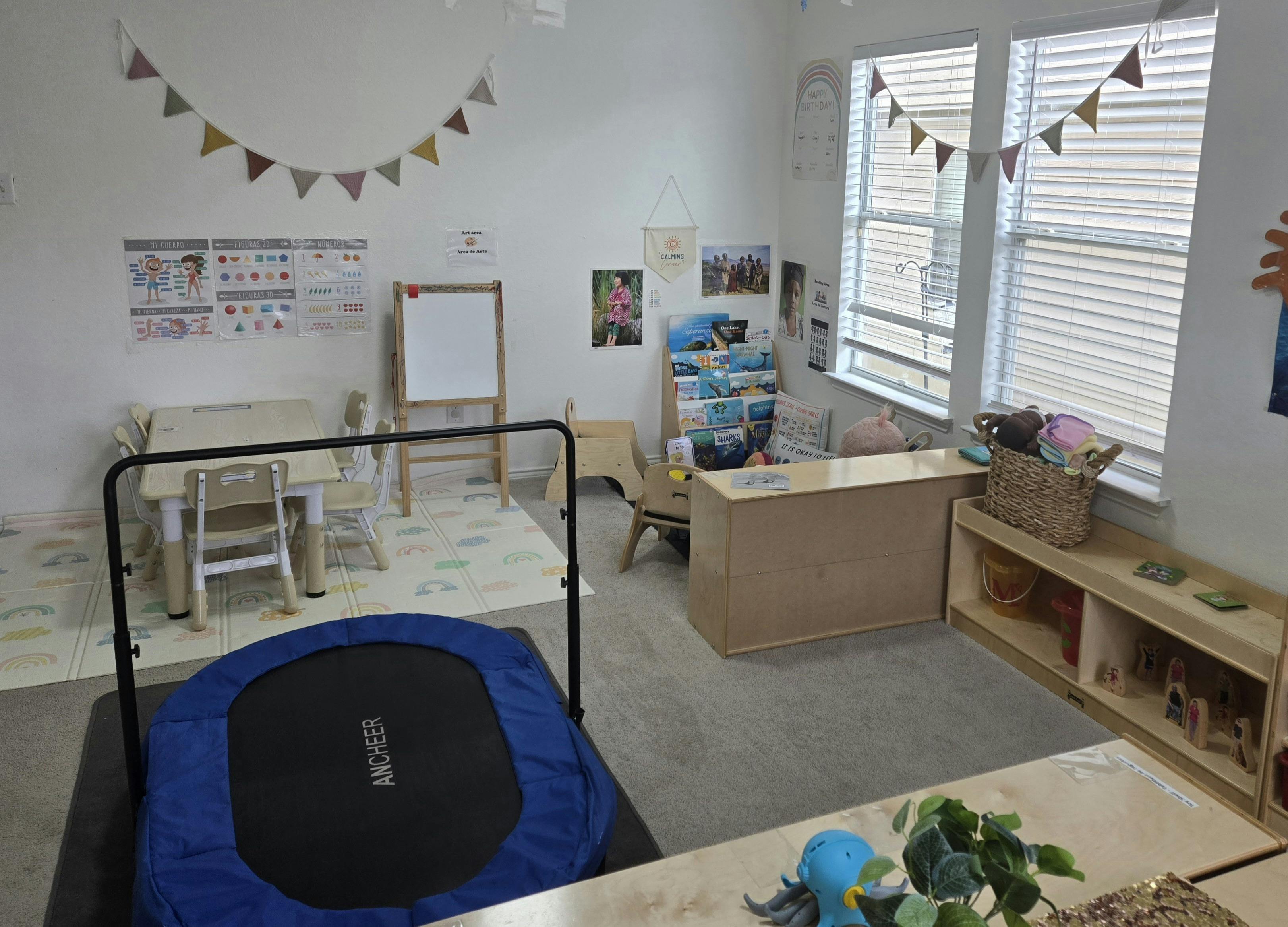 Indoor play area with a small trampoline, tables, and shelves