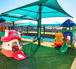 Playground with playhouses and slides under a shade structure