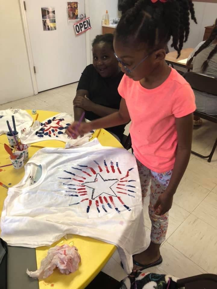 Child painting a star design on a white t-shirt