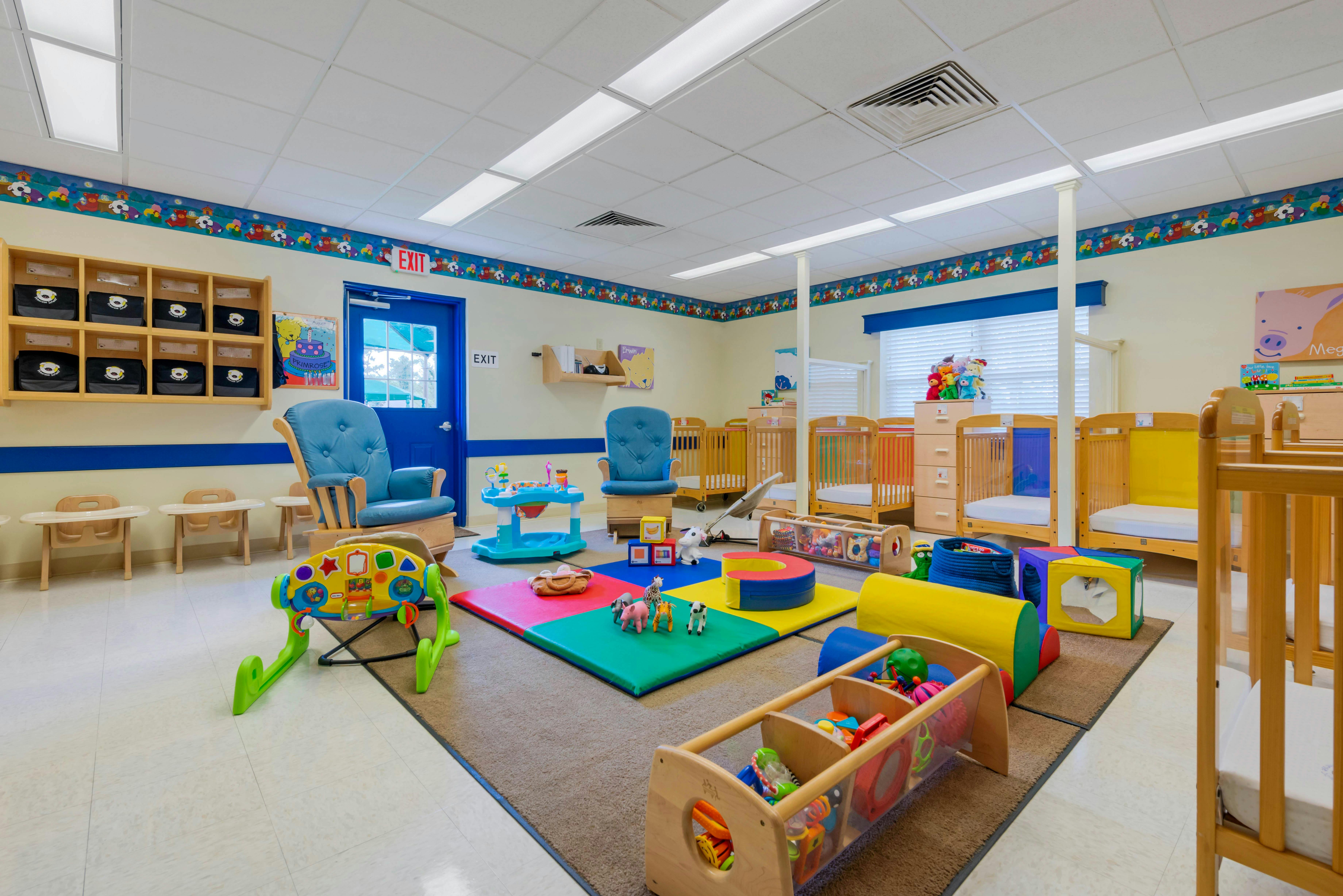 An empty nursery with cribs, playmats, and toys