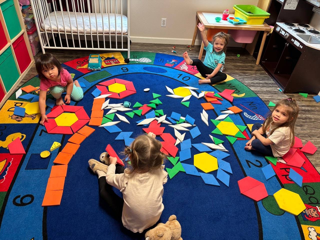 Four children playing with colorful shapes on a rug
