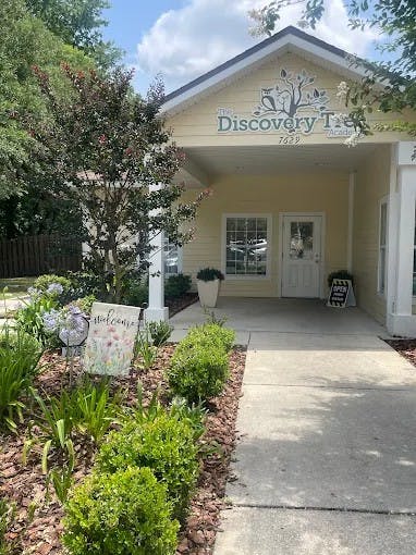 Building entrance with "The Discovery Tree" sign and a welcome sign in the garden