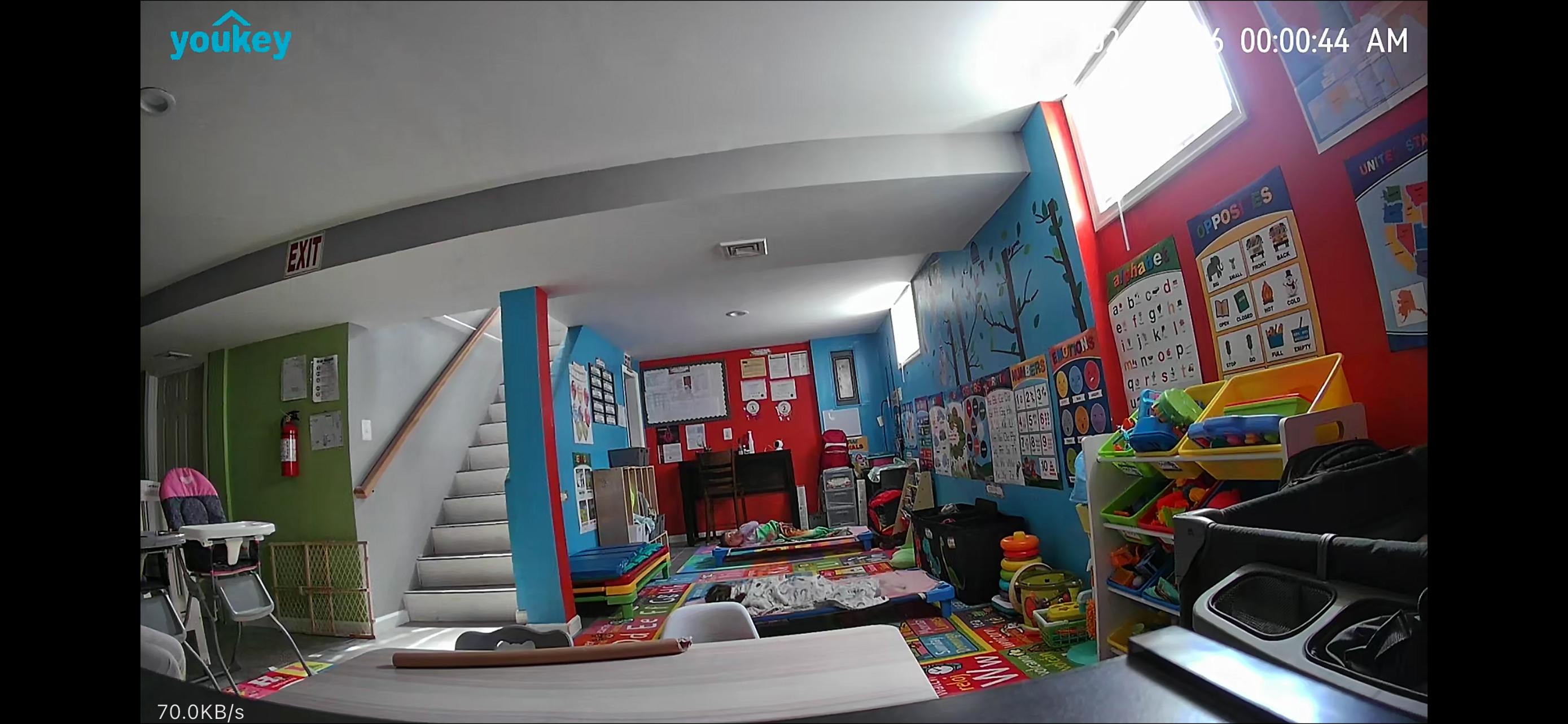 Child resting on a mat in a brightly colored preschool classroom