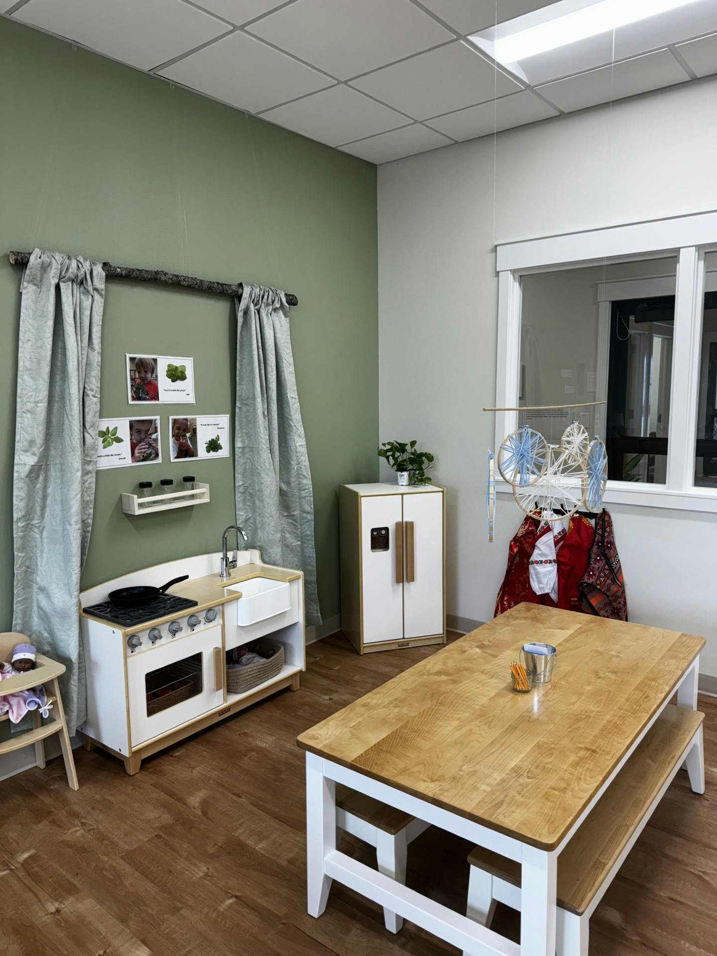 Play kitchen area with a toy stove, sink, and refrigerator