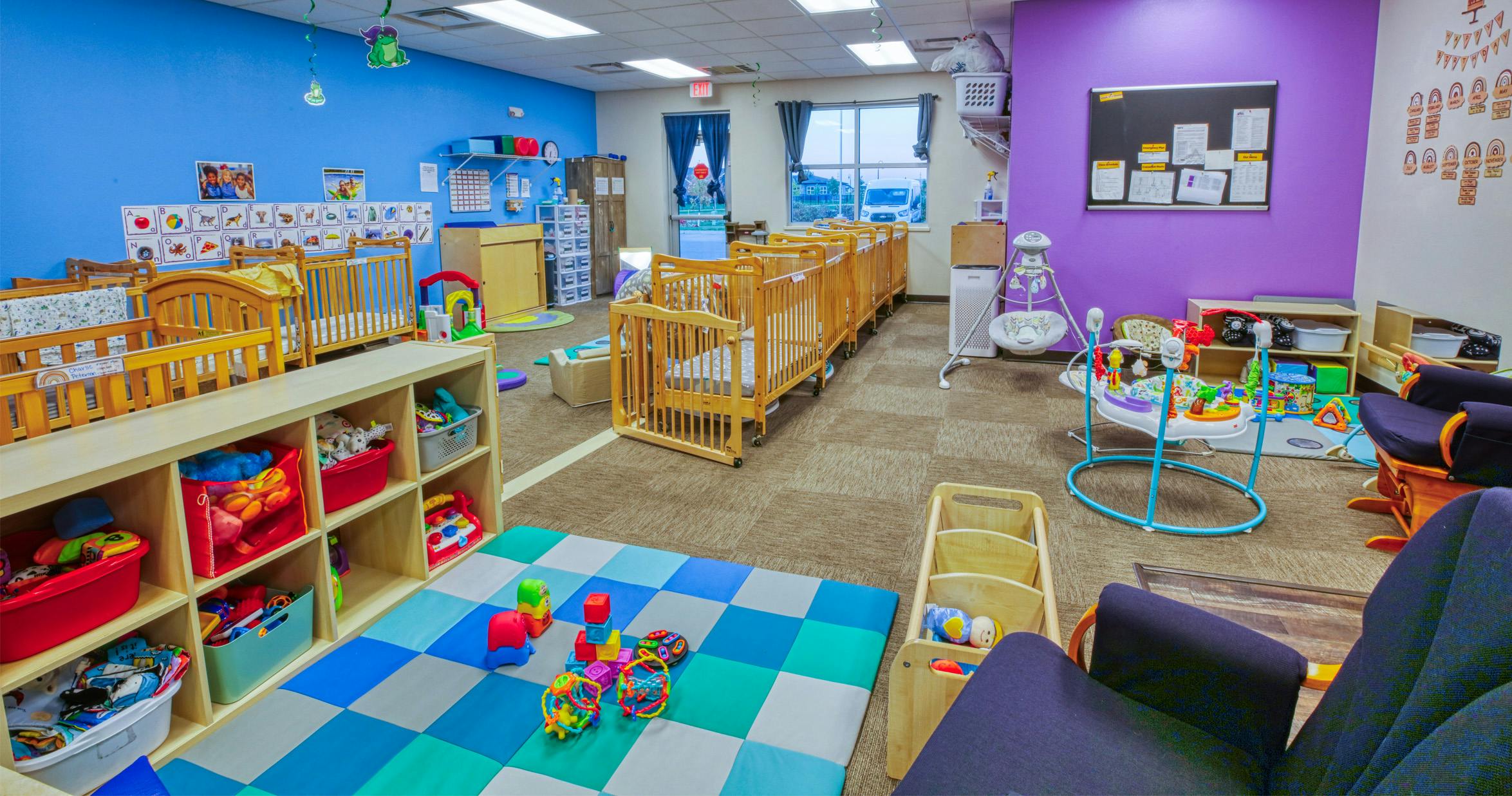 Baby room in a daycare with cribs, play mats, and toys