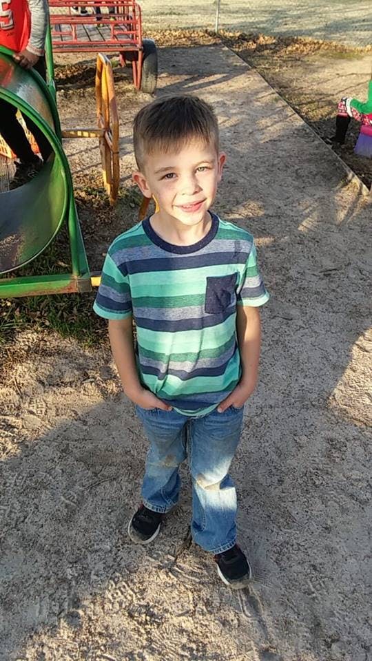 Child in striped shirt and jeans standing with hands in pockets