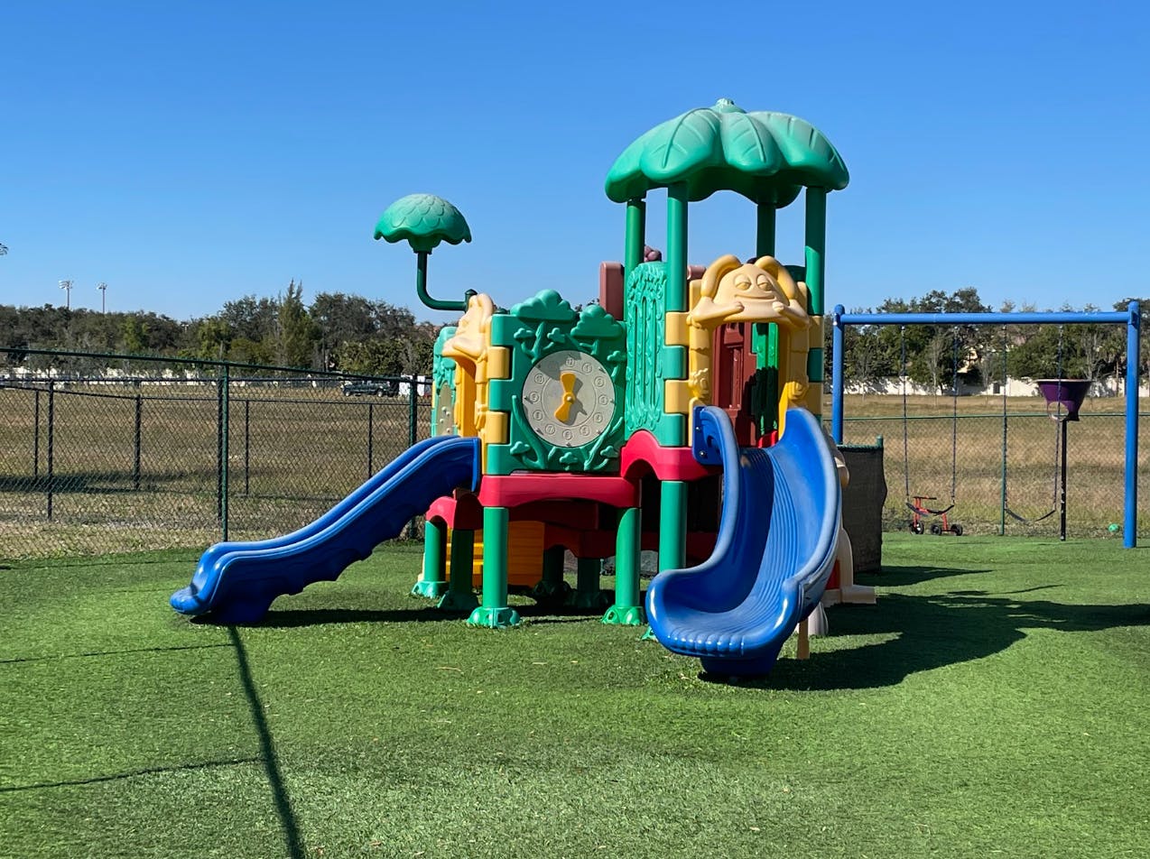 Colorful playground structure with two blue slides and a swing set