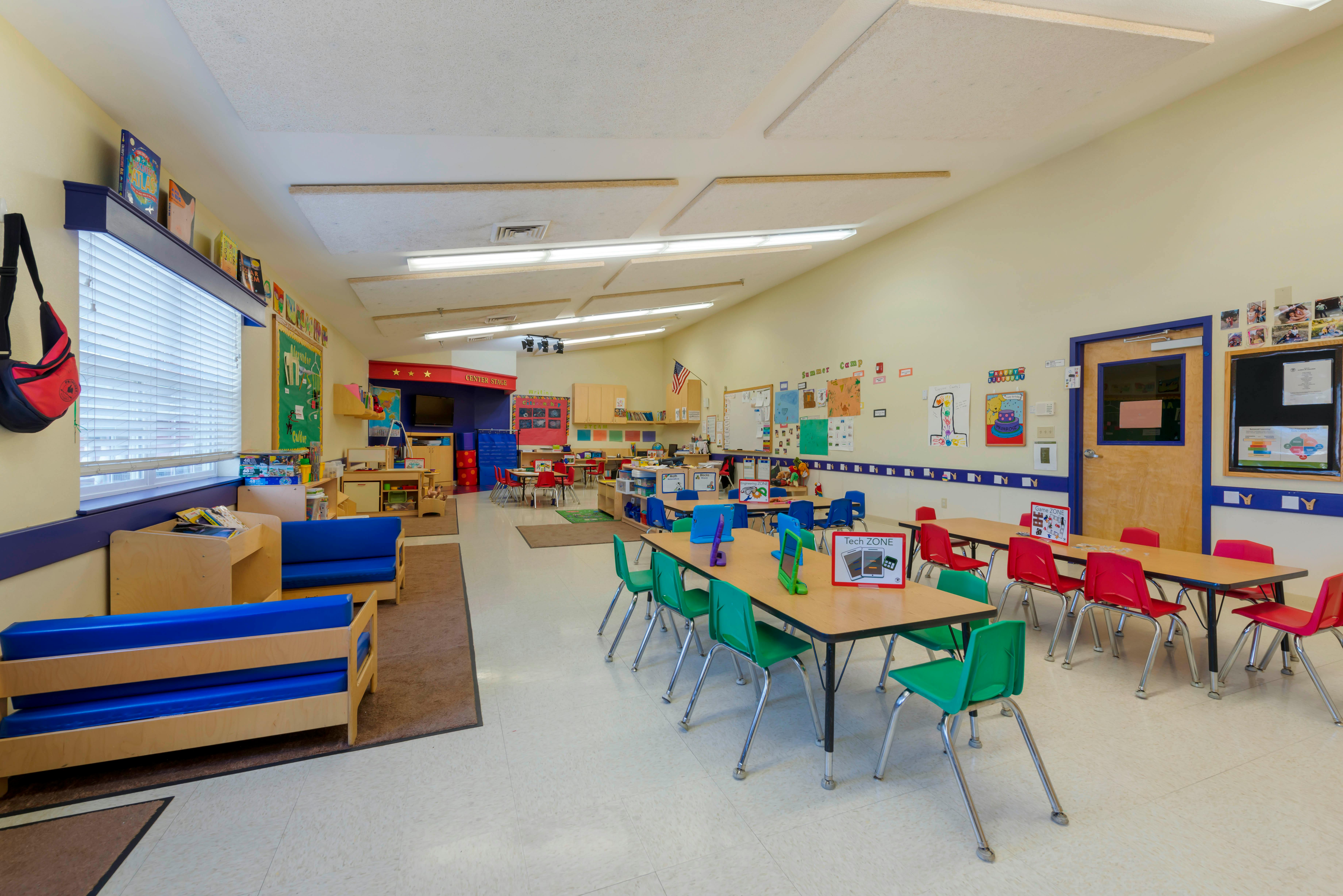 Classroom with small tables and chairs, activity centers, and a 'Center Stage'