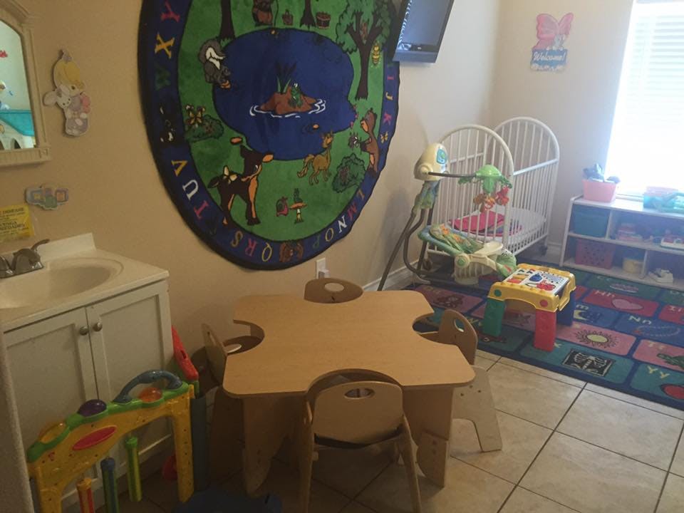 Child's playroom with small table and chairs, crib, and colorful rug